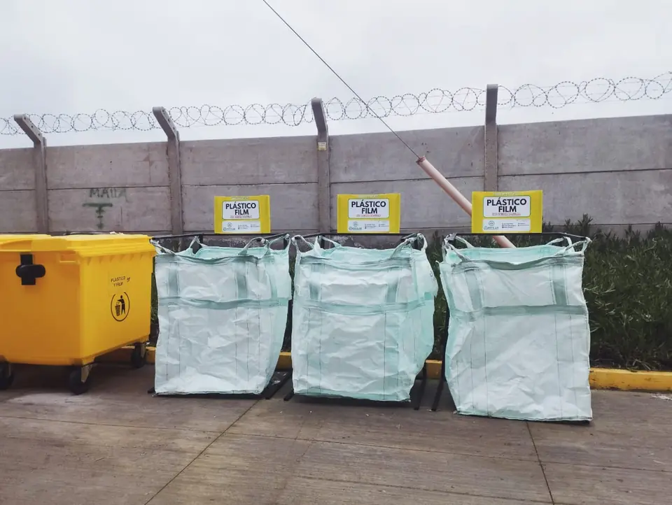 Tres maxisacas rotuladas con el letrero «Plástico film», junto a un contenedor amarillo